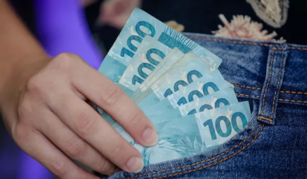 Pessoa tirando notas de R$ 100 do bolso