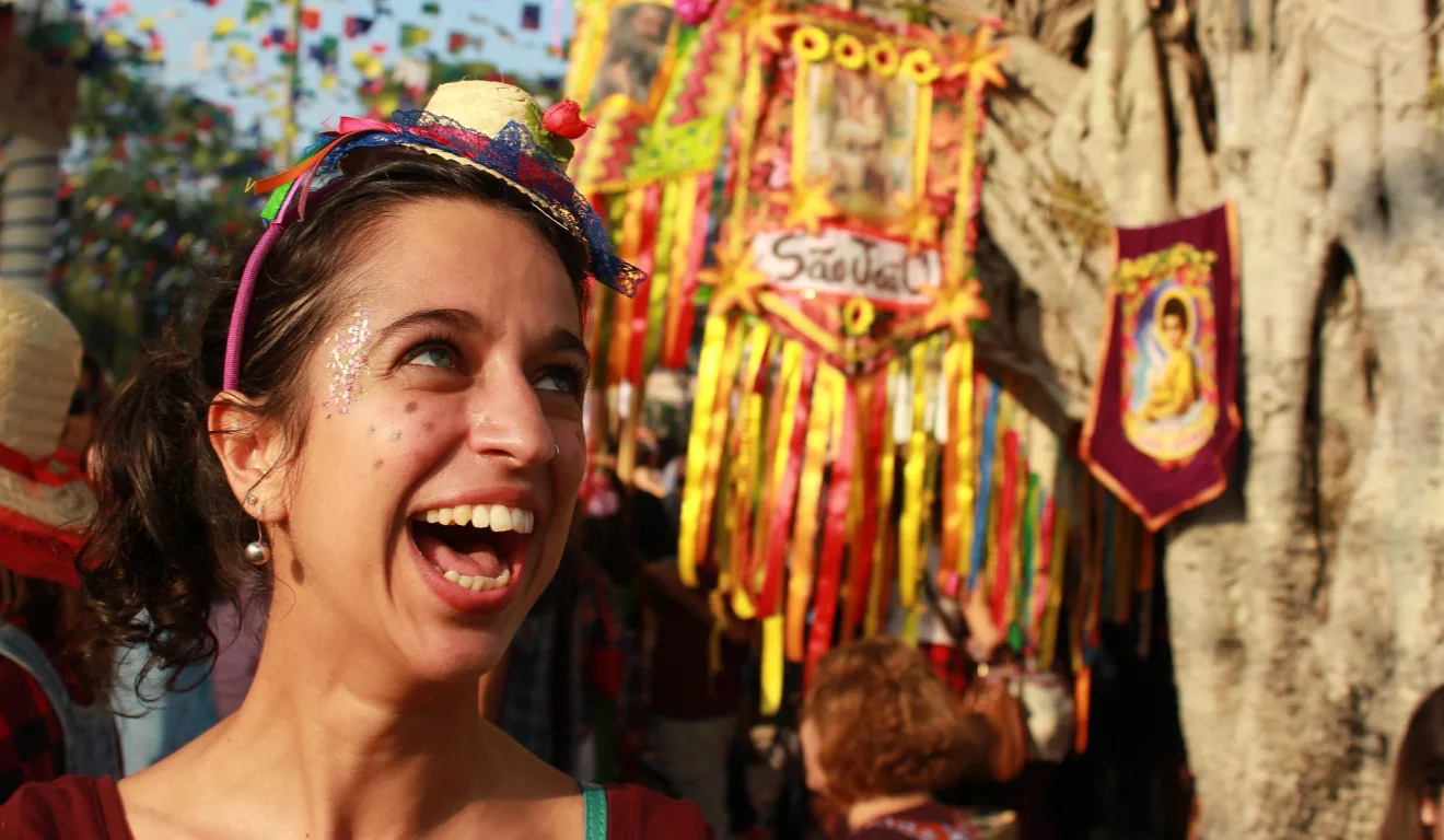 Imagem de uma mulher com chapéu sorrindo em uma festa junina.