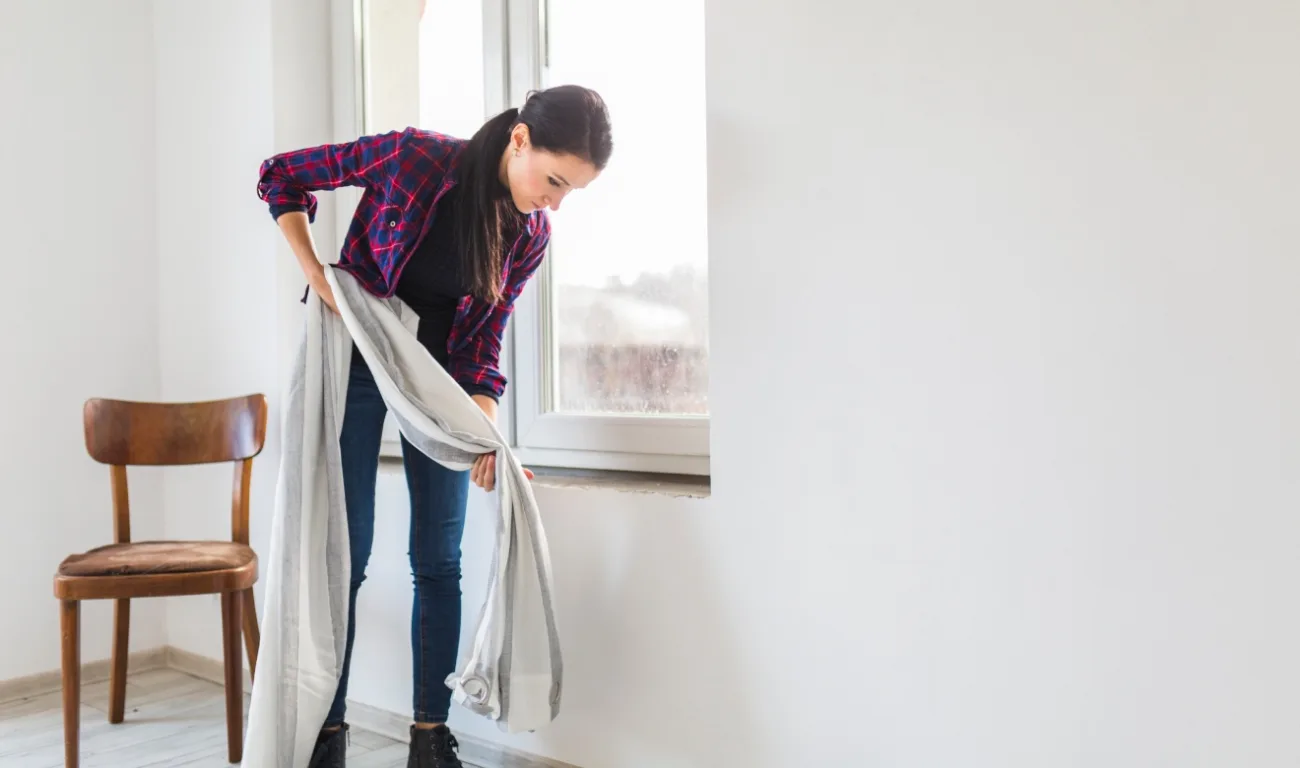 mulher com cortina na mão procurando mofo