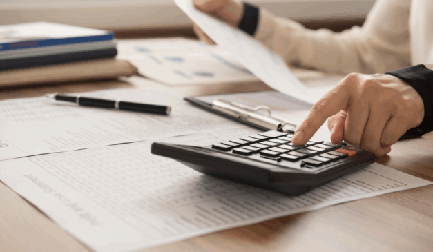 homem fazendo cálculos, com contas na mão e digitando na calculadora