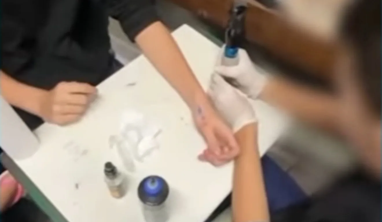 aluno tatuando outro