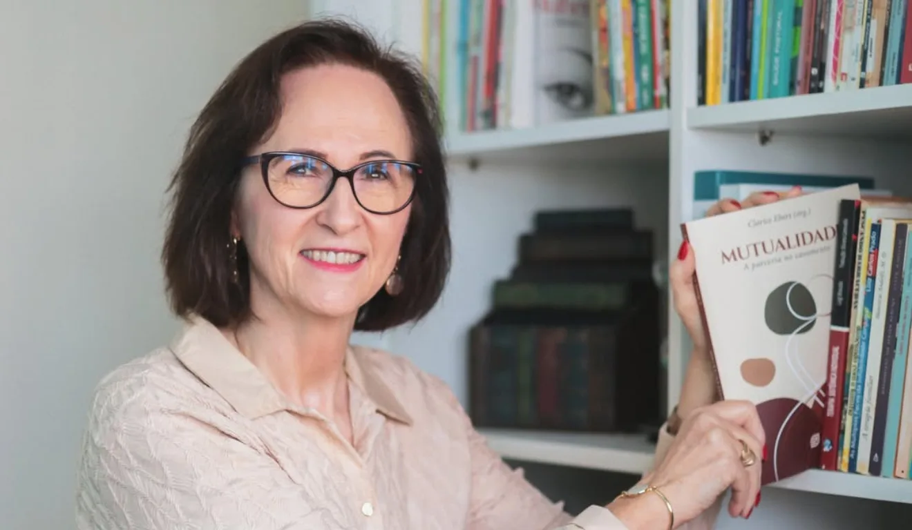 Imagem de Clarice Ebert segurando o novo livro 'Mutualidade'.