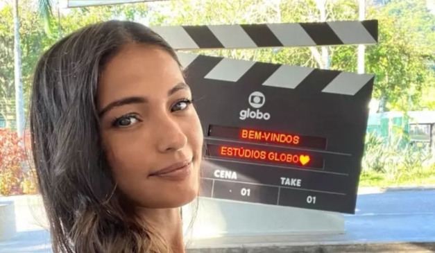 Atriz que mudou de nome posa na frente de emblema na Globo
