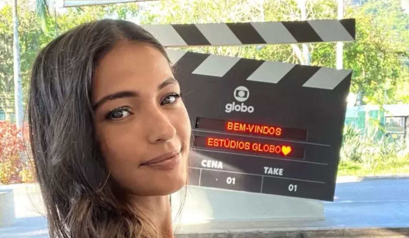 Atriz que mudou de nome posa na frente de emblema na Globo