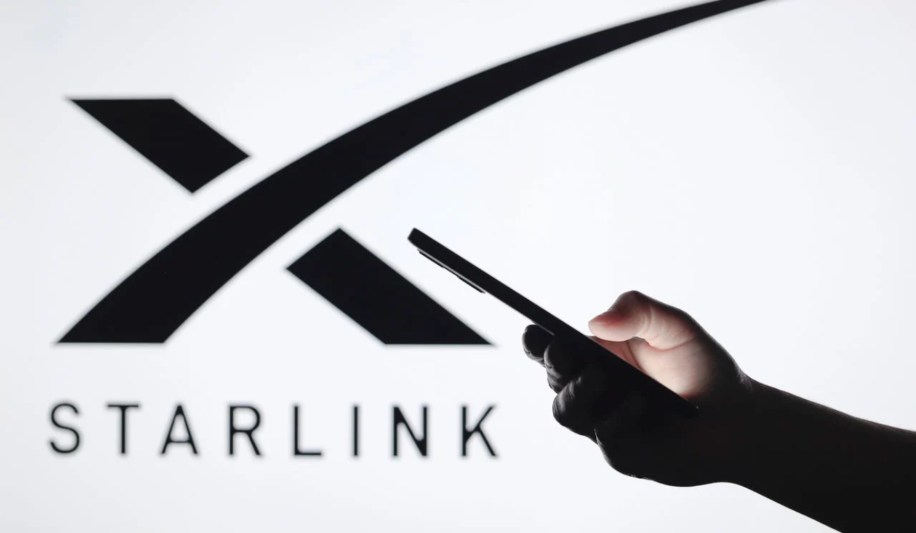 Celular na frente da logo da Starlink.