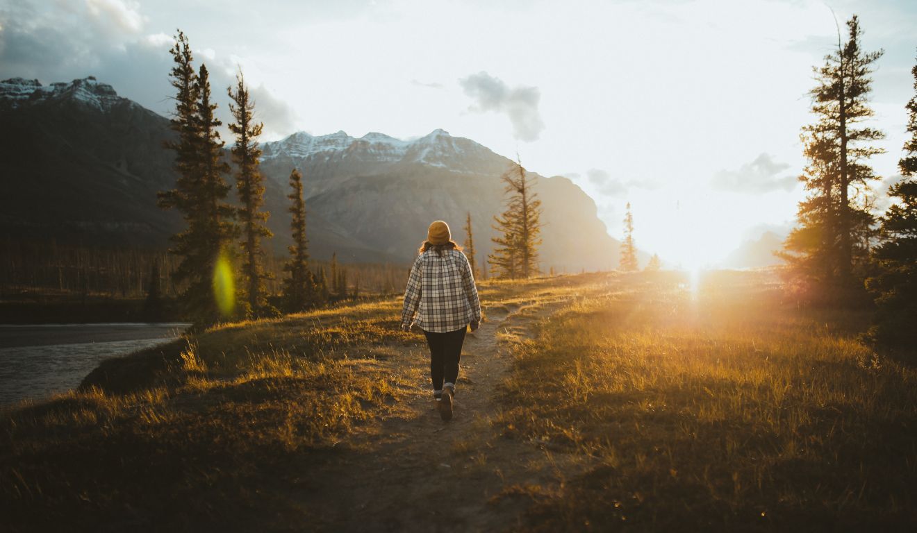 pessoa andando em meio às árvores para ilustrar o banho de floresta