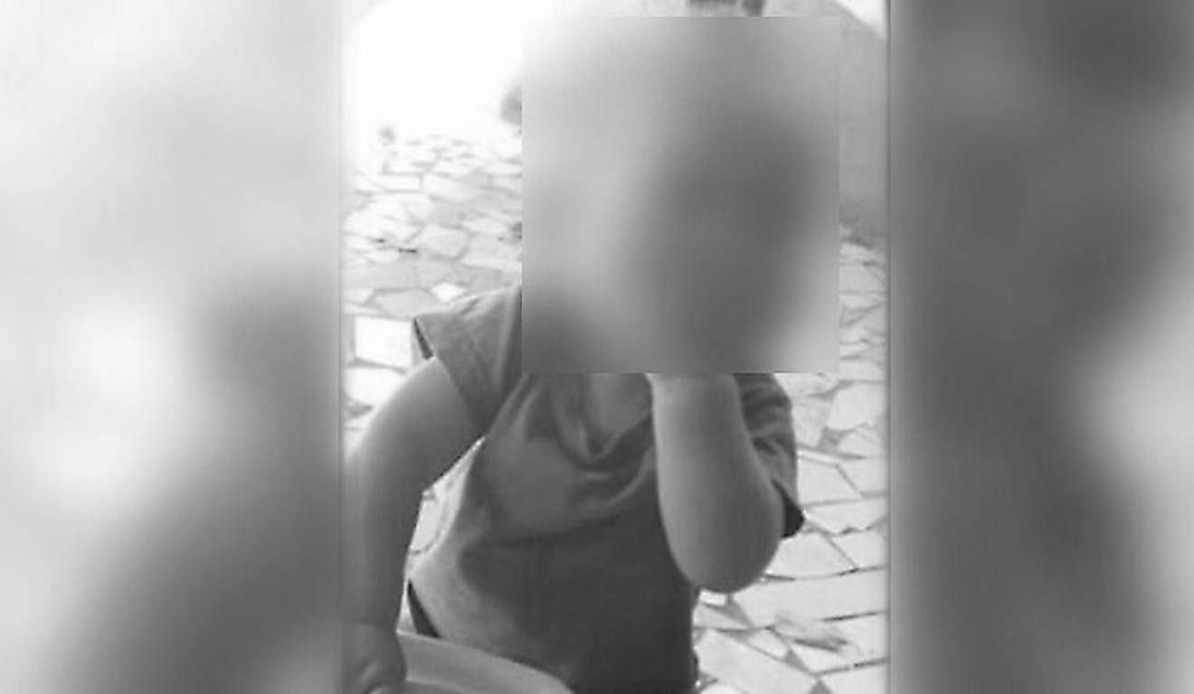 bebê que morreu afogado em balde de água em foto com mão na boca