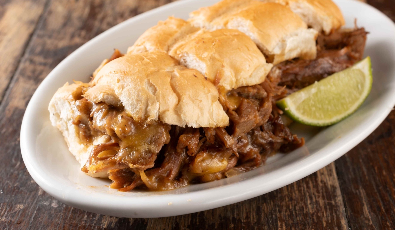 Sanduíche de carne desfiada com queijo, servido no pão francês, do cardápio de boteco em Curitiba.