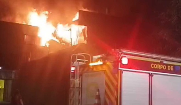 Incêndio atingindo confeitaria e corpo de bombeiros apagando