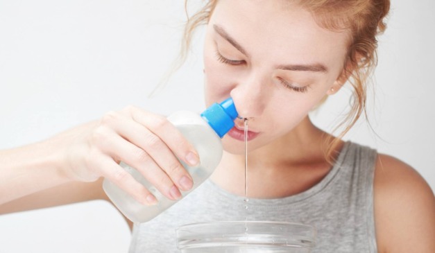 Mulher com garrafinha de lavagem nasal na mão