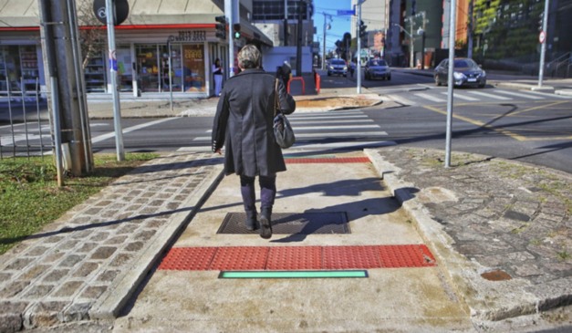 Mulher atravessando a rua em meio a sinalização de led em travessia de Curitiba