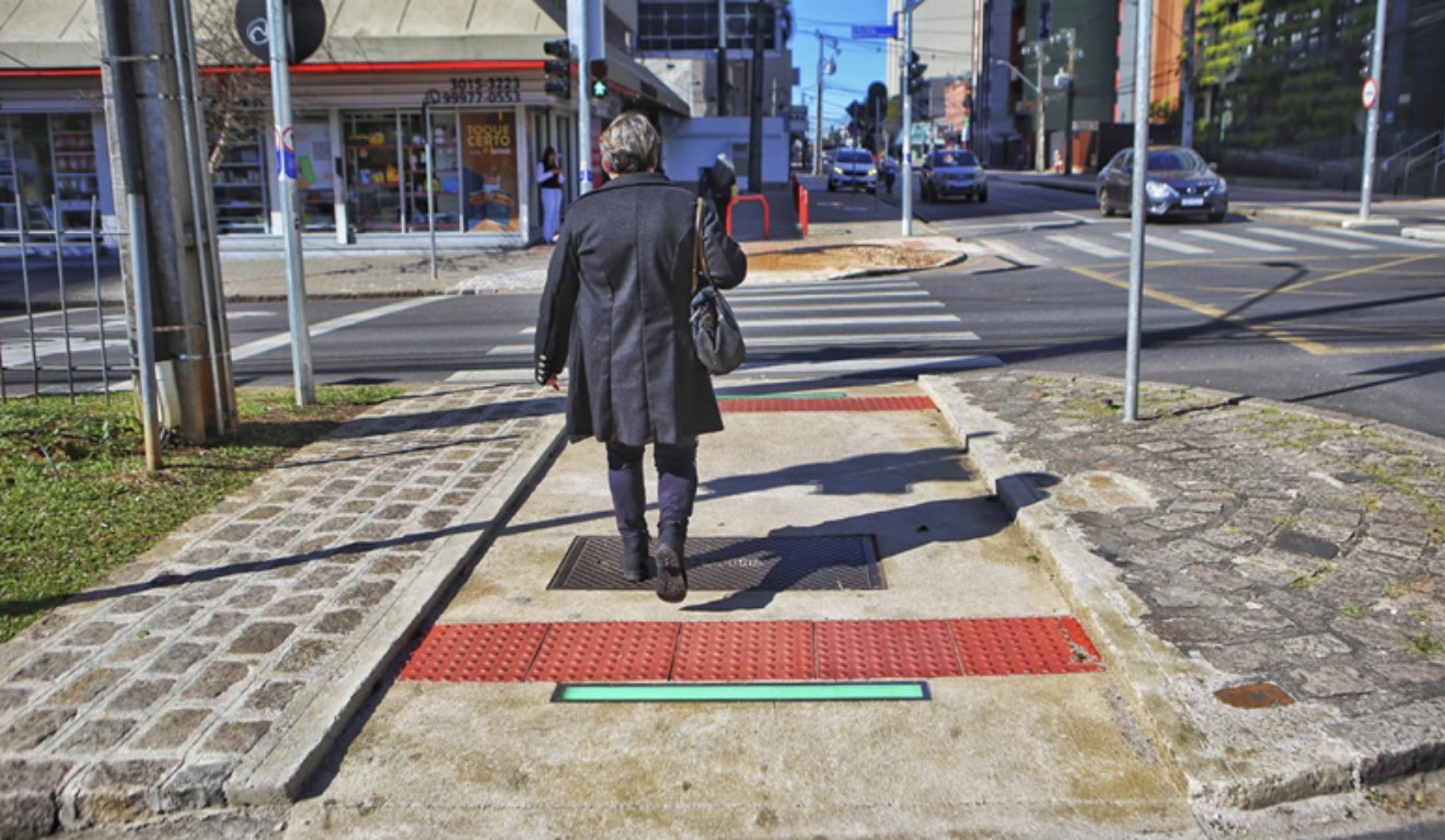 Mulher atravessando a rua em meio a sinalização de led em travessia de Curitiba