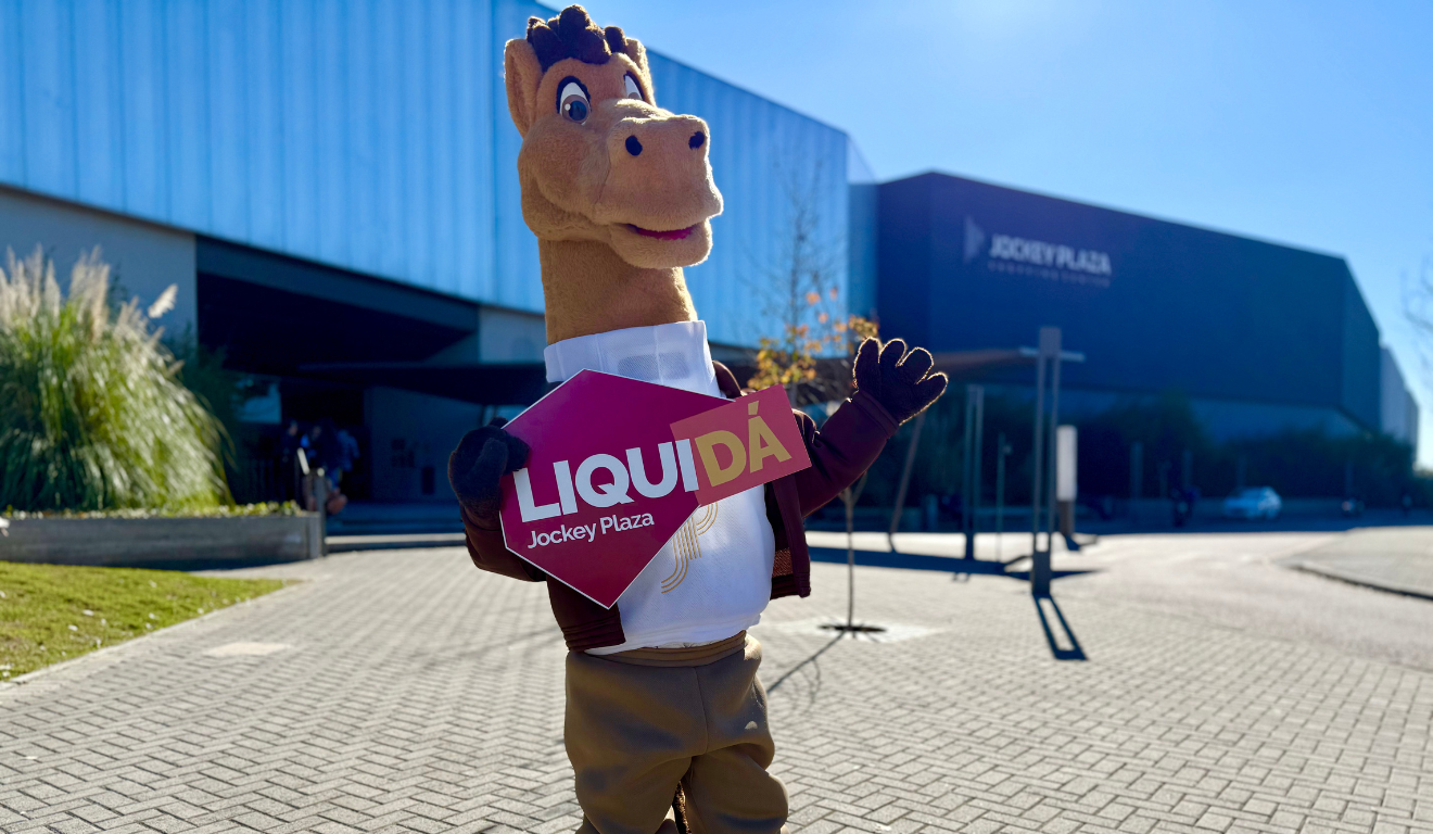 mascote do Jockey Plaza Shopping com placa da promoção LiquiDa, em frente ao shopping