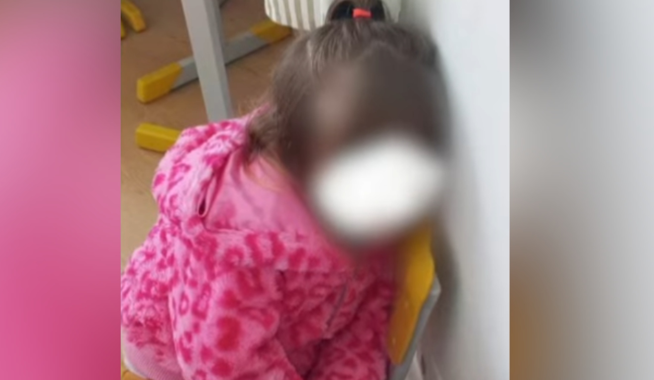 Menina amarrada escola aparece sentada com cabeça encostada na parede