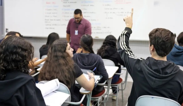 Alunos com a mão levantada em sala de aula