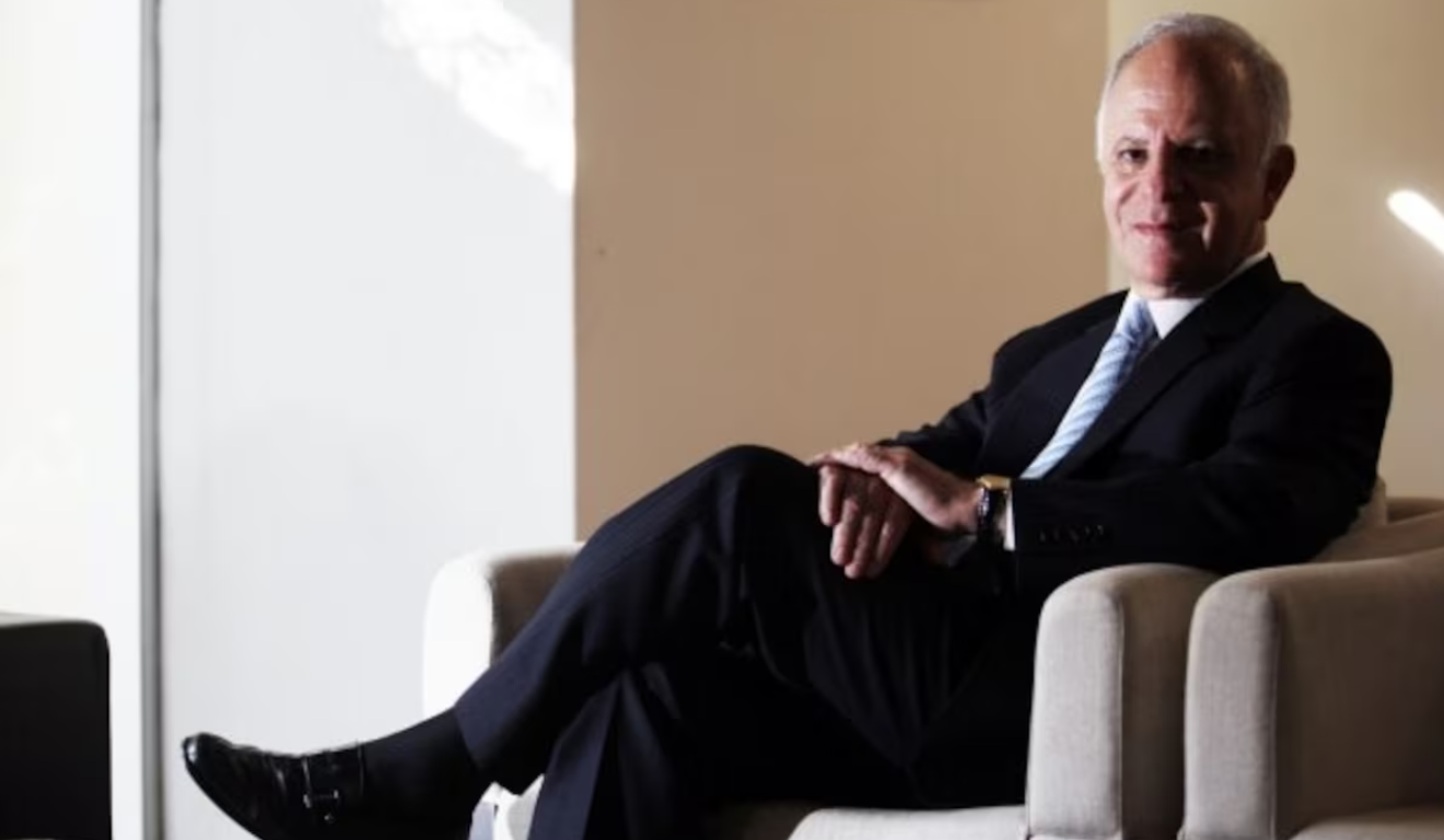 O oitavo homem mais rico do Brasil, Miguel Krigsner, é formado pela UFPR. Miguek é um homem branco, de cabelo grisalho, que usa um blazer preto, camisa branca, calça social preta e sapato preto.