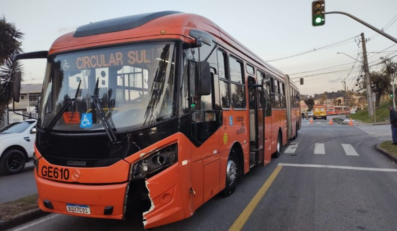 Um ciclista morreu após colidir e ser atropelado por um ônibus em Curitiba. Na imagem vemos um biarticulado vermelho da linha Circular Sul com o parachoque danificado.