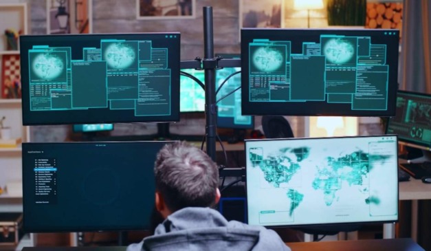 Homem em frente a telas de computador