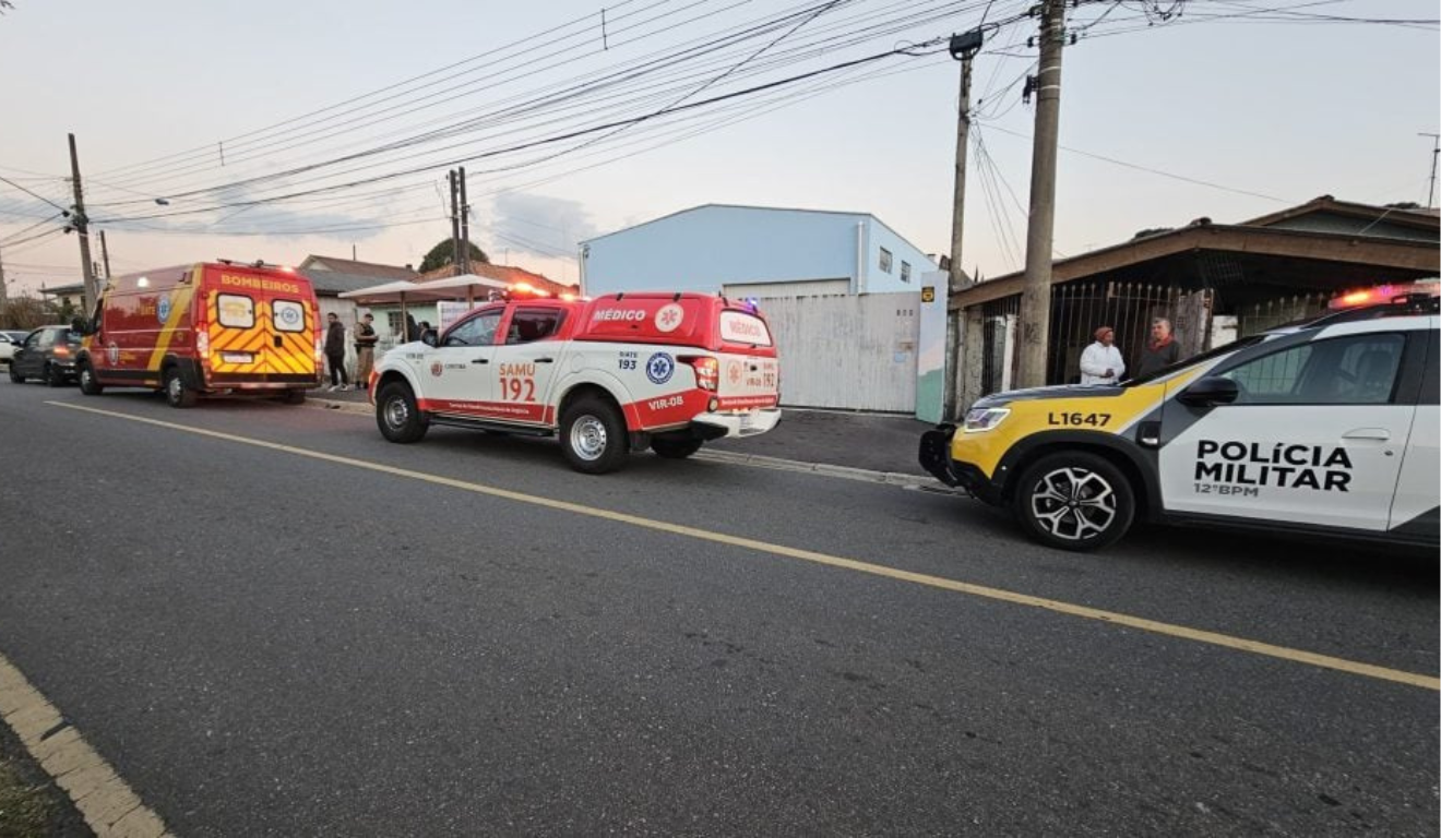 Da esquerda para a direita, vemos uma ambulância dos bombeiros, um carro do SAMU e uma viatura da Polícia Militar estacionadas no local do crime.
