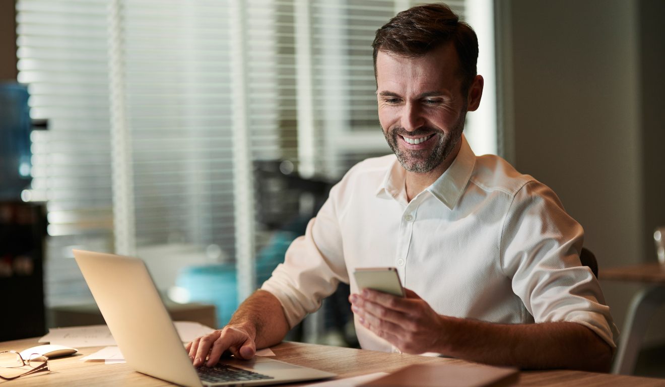 Homem olhando celular e sorrindo.