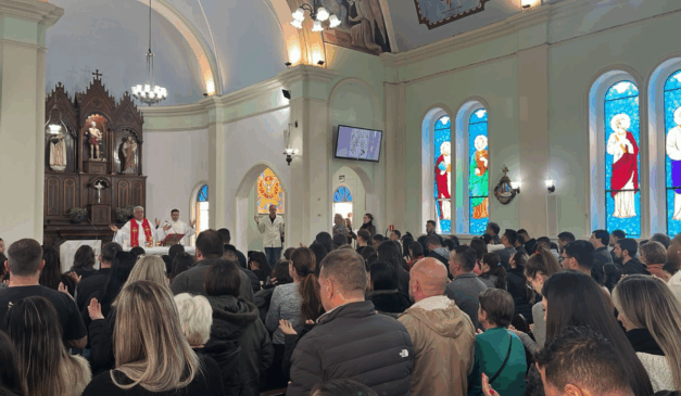 Pessoas dentro de paróquia orando e prestando homenagens.