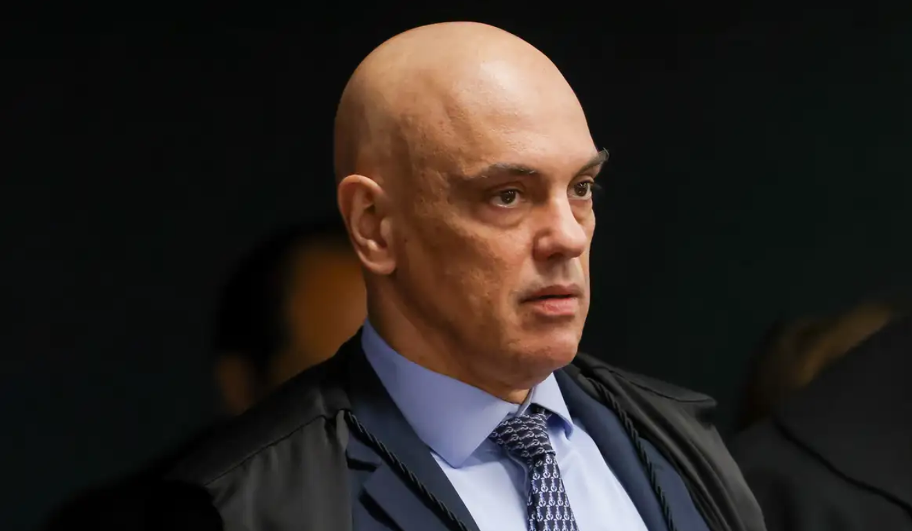 Na imagem, o ministro do STF Alexandre de Moraes, que disse que bancos podem ser punidos se aplicarem sanções americanas. Moraes é um homem branco e careca. Na foto, ele utiliza um blazer azul escuro, uma camisa azul clara e uma gravata azul escuro.
