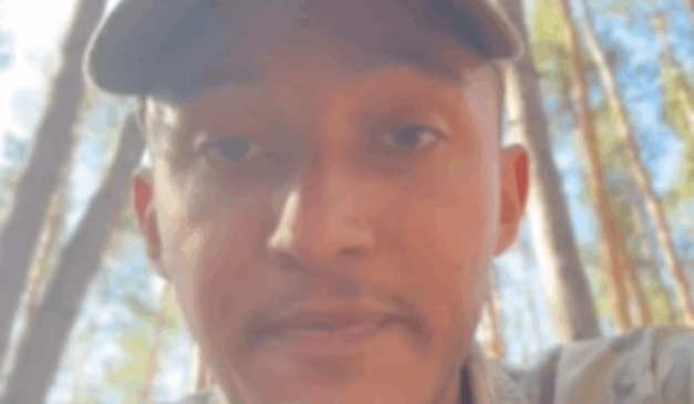 Imagem do rosto de Lucas Felype Vieira Bueno, de 20 anos, utilizando um boné, em meio a uma região de mata.