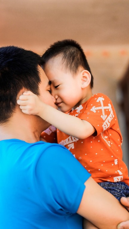 Pai com filho no colo em expressão afetiva mútua.
