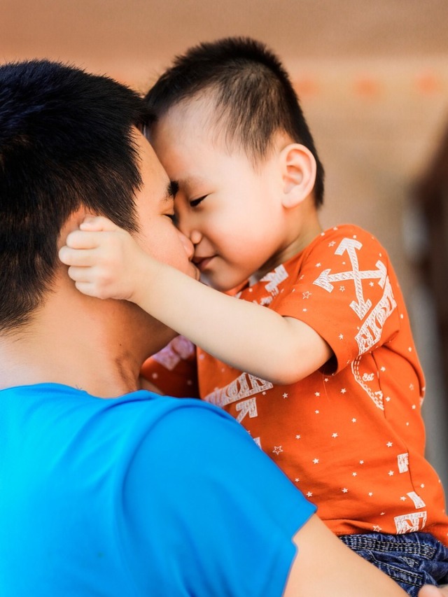 Pai com filho no colo em expressão afetiva mútua.