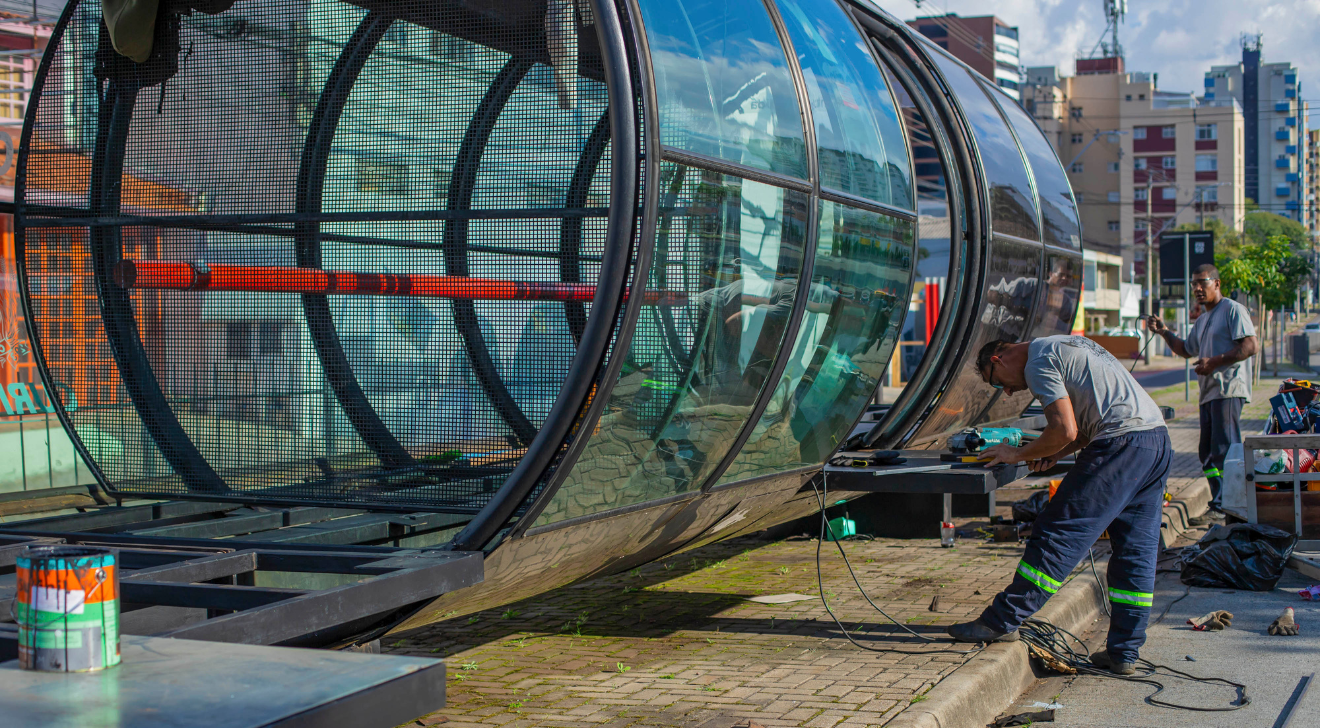 dois trabalhadores reformam uma estação-tubo de Curitiba