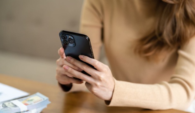 mulher mexendo no celular para ilustrar a que fingiu o próprio sequestro para apostar no jogo do tigrinho