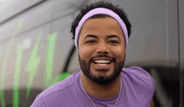 STJ mantém a prisão de Hytalo Santos. Na imagem, vemos o influenciador sorrindo para a foto, utilizando uma camiseta roxa e uma faixa roxa no cabelo. Hytalo Santos é um homem negro de cabelo e barba pretos.