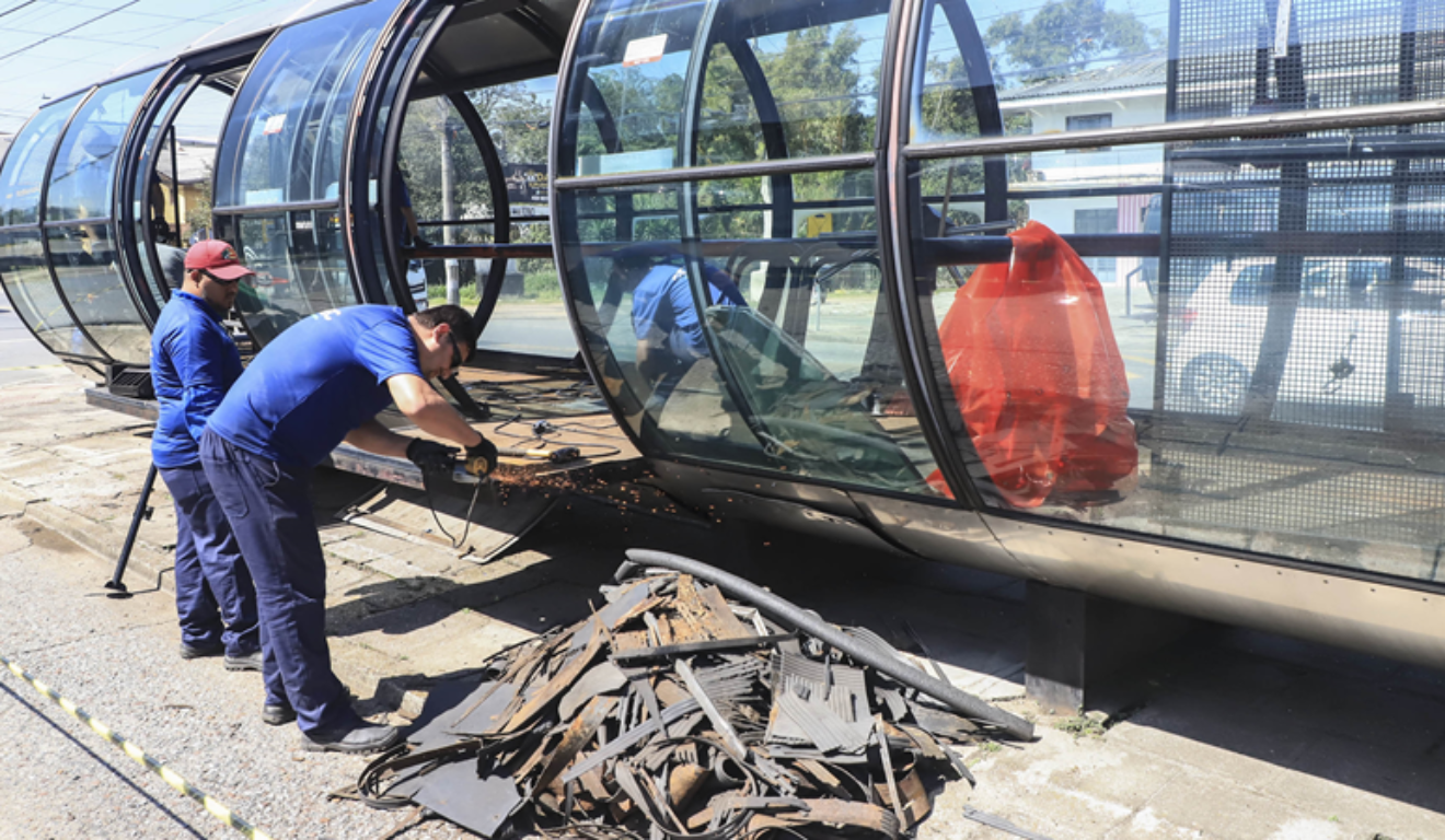 Na imagem, vemos trabalhadores com ferramentas, fazendo obras em uma estação-tubo de Curitiba. Quatro estações-tubo da cidade serão desativadas na quarta-feira para serem revitalizadas.