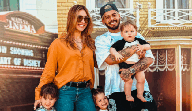 Zé Felipe, de camiseta branca, e Virgínia, de camisa amarela, lado a lado, com os trÊs filhos pequenos próximos, sorrindo.