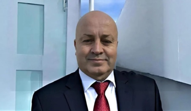 Careca do INSS usando terno e gravata vermelha