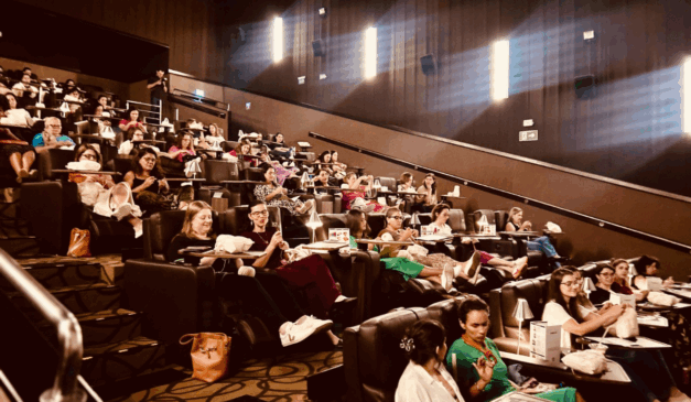Imagem da sala de cinema com pessoas fazendo crochê.