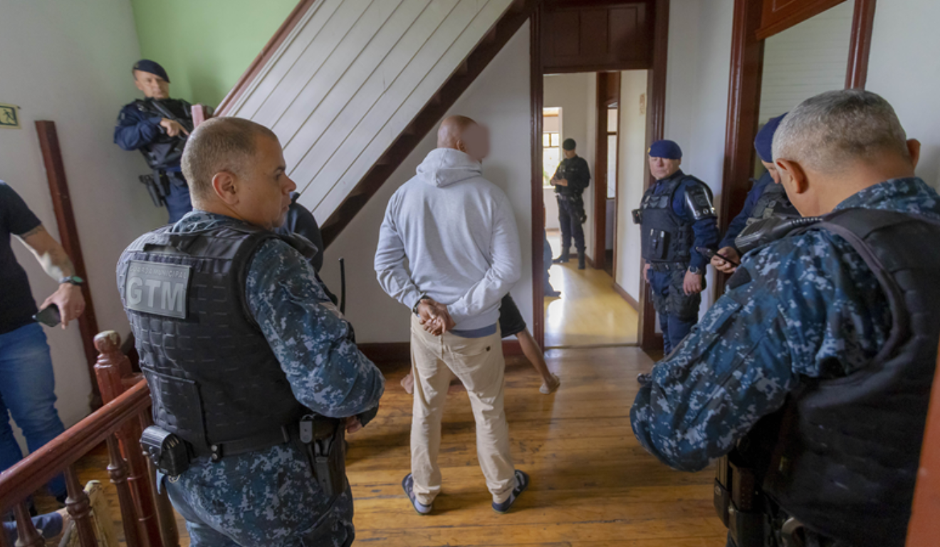 Um hotel foi interditado e cinco pessoas foram presas em Curitiba. Na imagem, vemos o interior de um dos hotéis, com agentes da Guarda Municipal e um dos detidos em flagrante.