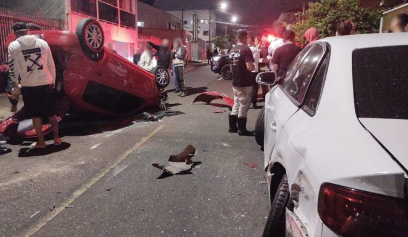 Um jovem sem CNH capotou o carro em Curitiba. Na imagem, vemos o Renault Clio vermelho capotado no meio da rua, com pedaços do carro no asfalto.