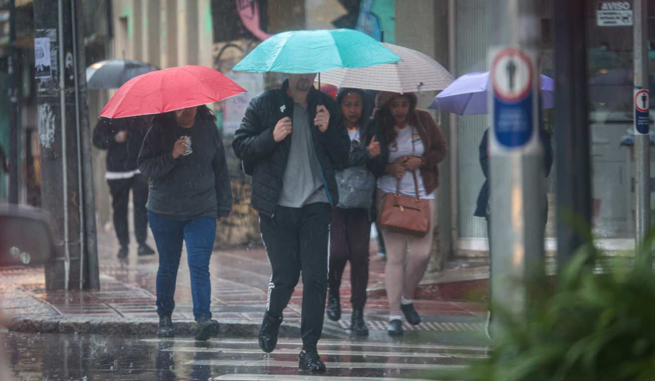 Pancadas de chuva atingindo o Paraná e pessoas andando com guarda-chuva