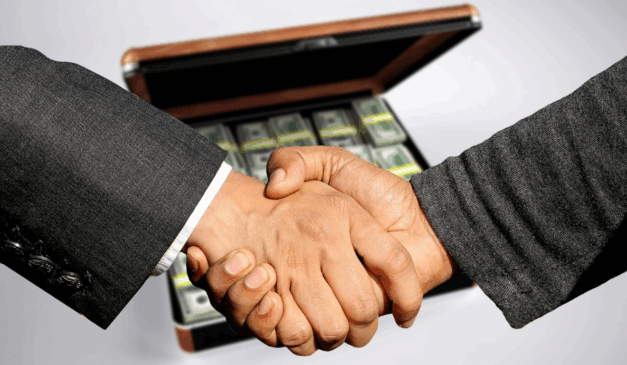 homens dando as mãos, ao fundo mala de dinherio, sugerindo corrupção