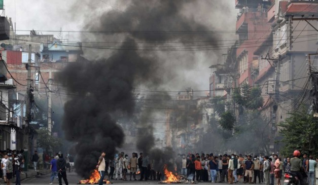 O Exército começou a ocupar as ruas após os protestos no Nepal. Na foto, vemos várias pessoas durante um protesto queimando objetos.