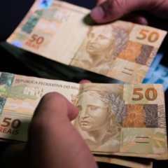 13º salário: cédulas de dinheiro nas mãos