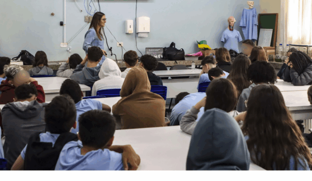A partir de outubro de 2025, diversas escolas de Curitiba terão ar-condicionado nas salas de aula. Na imagem, vemos uma professora explicando um conteúdo para seus alunos.