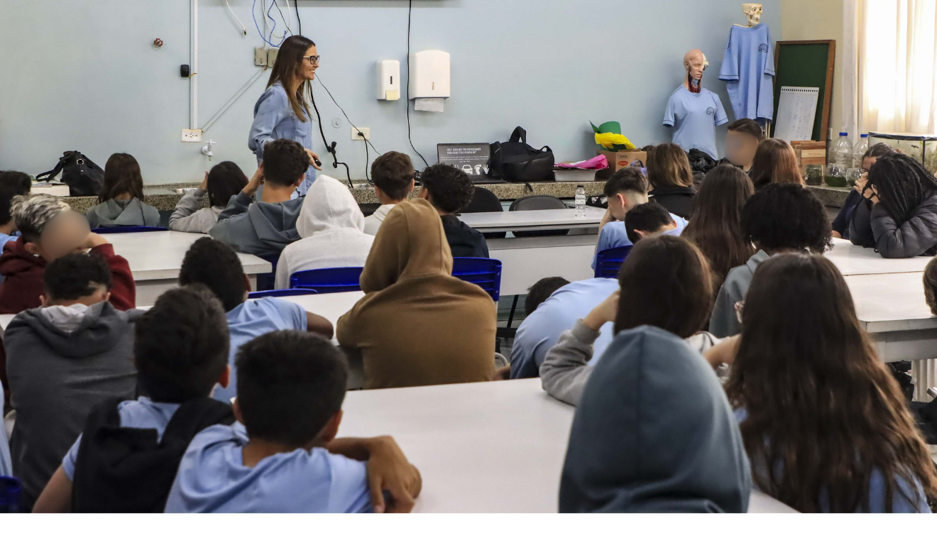 A partir de outubro de 2025, diversas escolas de Curitiba terão ar-condicionado nas salas de aula. Na imagem, vemos uma professora explicando um conteúdo para seus alunos.