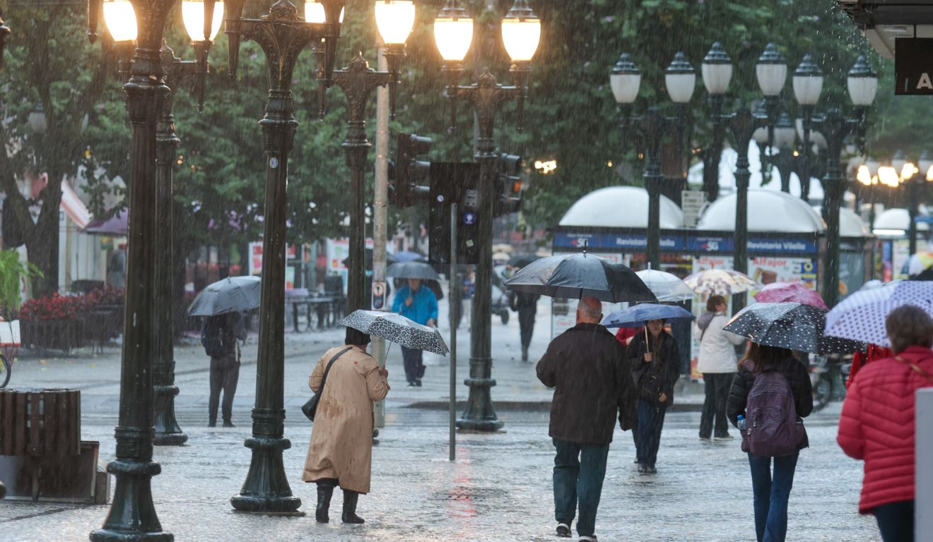 pessoas andando na chuva para ilustrar a chegada da frente fria