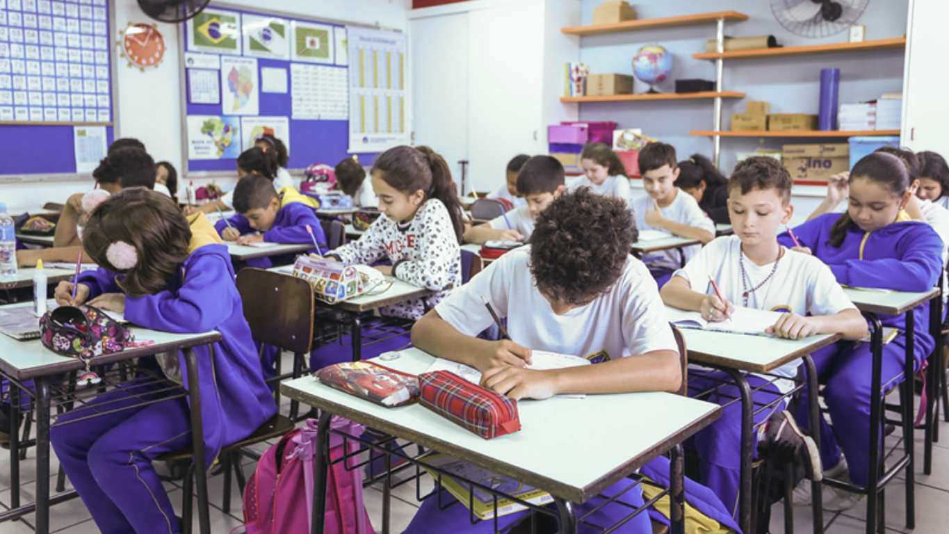 sala de aula lotada com crianças estudando sentadas