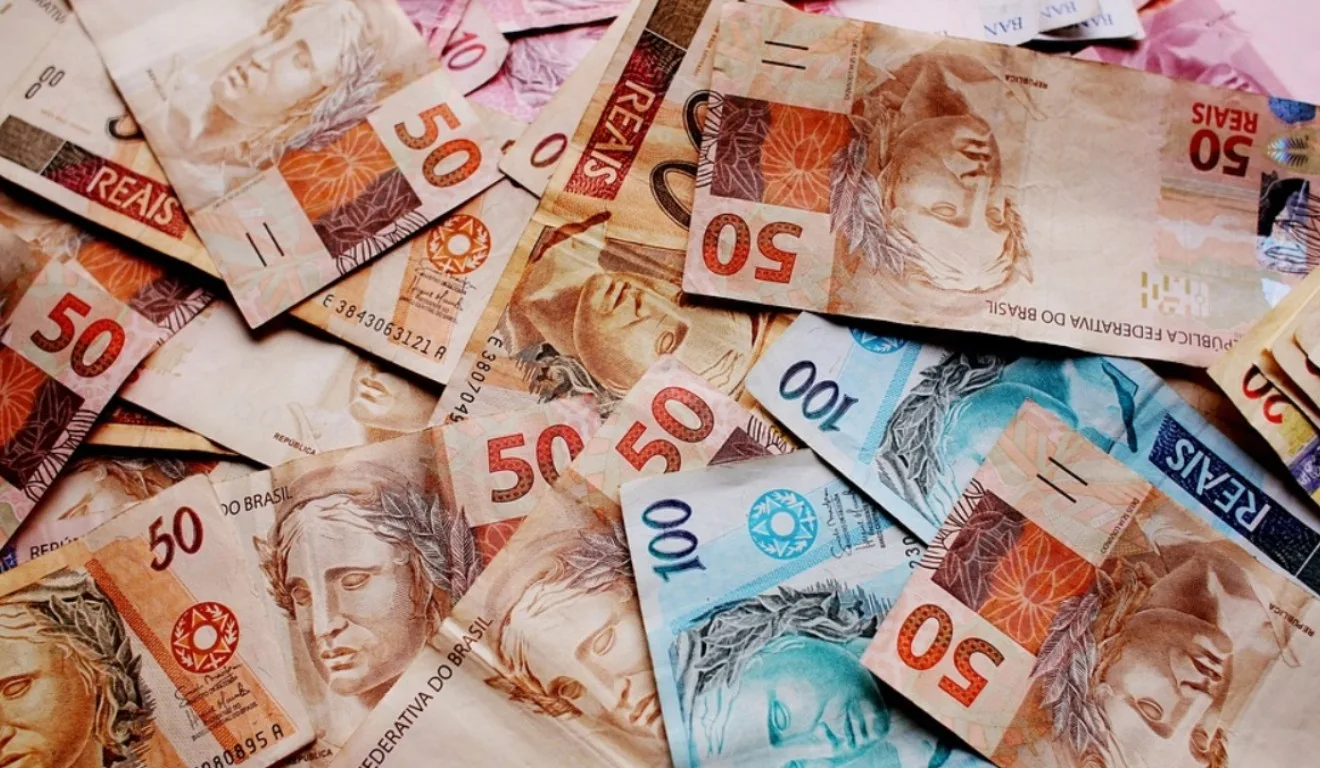 Descubra a História da Loteria Federal. Na imagem, vemos diversas notas de R$ 100, R$ 50, R$ 20 e R$ 10.