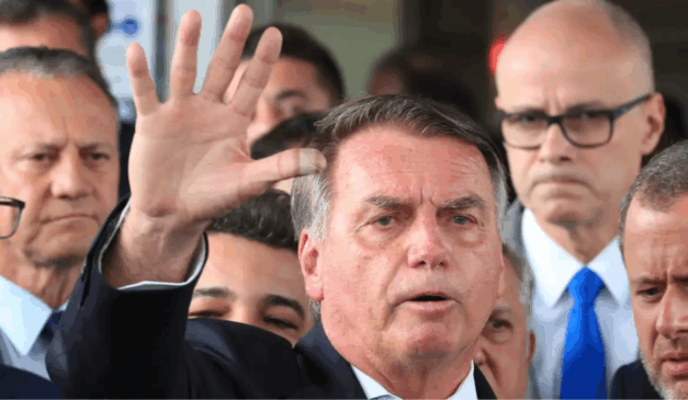 Em 2026 deve ser lançado o filme "Dark Horse" ("O azarão") sobre a história de Jair Bolsonaro. Na imagem vemos o ex-presidente Bolsonaro, um homem branco de cabelo castanho, usando um blazer preto e com o braço direito estendido e a mão aberta.