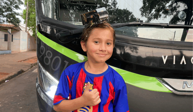 João Gabriel, de 10 anos, com uma réplica de um ônibus preto e dourado G8 da Viação Garcia, modelo que celebra os 90 anos da empresa.