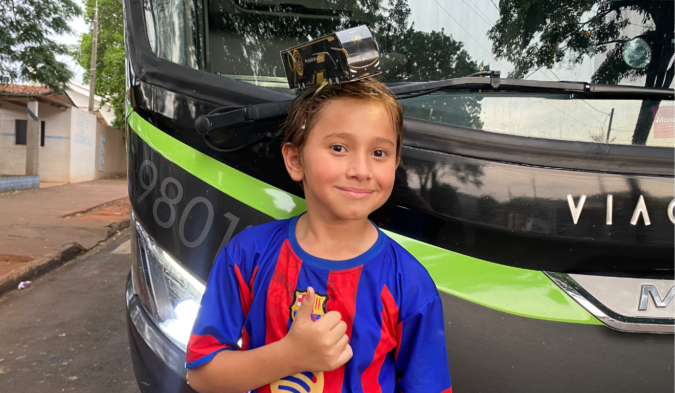 João Gabriel, de 10 anos, com uma réplica de um ônibus preto e dourado G8 da Viação Garcia, modelo que celebra os 90 anos da empresa.